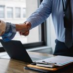 kézfogás írósztalnál laptop felett