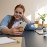 Portrait of woman using smartphone at home with pop socket