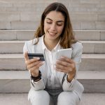 üzletasszony teleont néz másik kezében bankkártyát tart