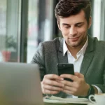 vállalkozó digitálisan ügyeket intéz laptop előtt, mobilon