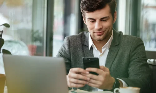 vállalkozó digitálisan ügyeket intéz laptop előtt, mobilon