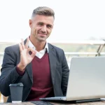 vállalkozó laptop előtt teraszon ülve ügyeket intéz
