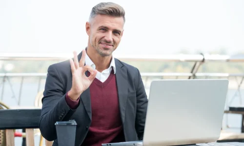 vállalkozó laptop előtt teraszon ülve ügyeket intéz