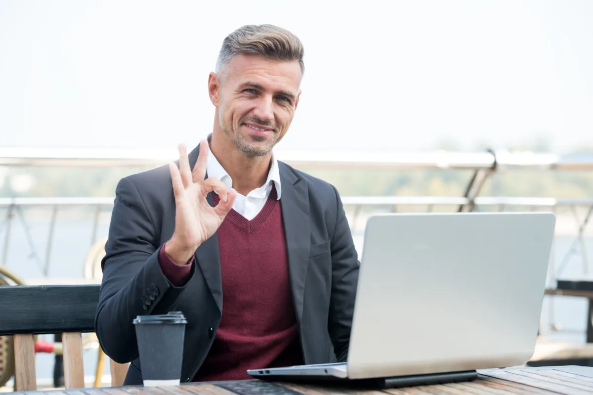 vállalkozó laptop előtt teraszon ülve ügyeket intéz