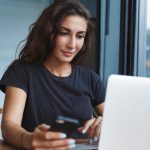 csinos nő laptop előtt mobillal számlát nyit