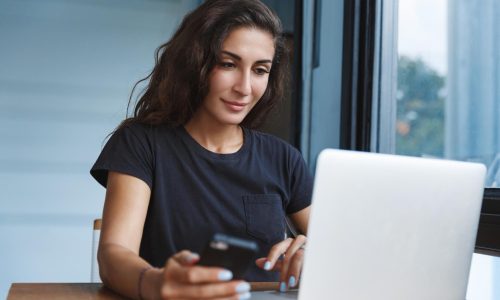 csinos nő laptop előtt mobillal számlát nyit